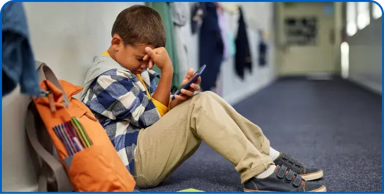 Student in a school hallway using a mobile device